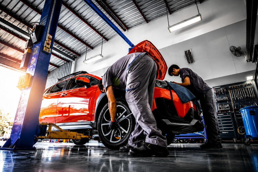Automotive repair shop — mechanics servicing a vehicle on a lift